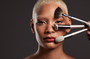 Image showing Woman, portrait and makeup brushes for beauty cosmetics, skincare or facial treatment against a gray studio background. Beautiful female holding cosmetic brushing tools on face for self care or love