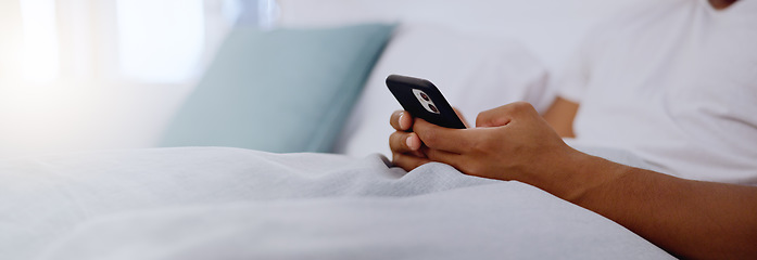 Image showing Typing, bed and hands of a man with a phone for social media, communication and chat. Contact, internet and guy scrolling on a mobile app for messages, reading emails or notification in the bedroom