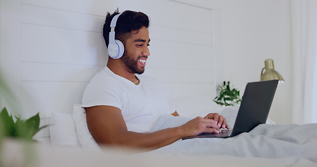 Image showing Movie, laughing and man in bed with a laptop for streaming, meme or comedy show online. Funny, relax and guy in the bedroom watching a film, subscription service or video on computer with headphones