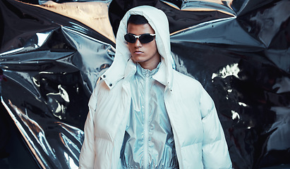 Image showing Holographic, sci fi and man with fashion and futuristic ski style with vaporwave clothing in studio. Art, creative and young male model with trendy, cool sunglasses and cyberpunk designer jacket