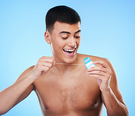 Image showing Dental floss, happy man and teeth cleaning for healthcare, wellness and morning care in studio. Blue background, male model and happy from hygiene with smile from healthy product for tooth protection