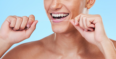 Image showing Happy man, dental floss and cleaning teeth in oral hygiene or grooming against a blue studio background. Closeup of male person with big smile in flossing, tooth whitening or gum and mouth care