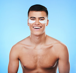 Image showing Happy man, beauty and smile with eye patch for skincare, grooming and clean with hygiene on blue background. Skin treatment, cosmetics product and wellness, portrait and dermatology in a studio