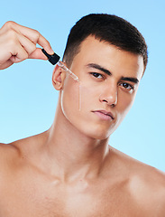 Image showing Man, serum and drop for face in studio with beauty, wellness and facial change by blue background. Young model, oil or hyaluronic acid for glow, shine and cleaning skin with cosmetic transformation