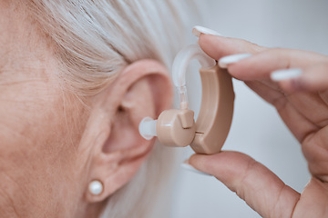 Image showing Hand, closeup and hearing aid in ear for old woman, audio or sound for listening, healthcare or retirement. Senior lady, deaf or person with disability holding technology for ear implant for wellness