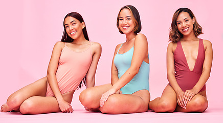 Image showing Diversity, swimsuit and portrait of happy women in studio, sitting together with smile and body positivity. Beauty, summer fashion and bikini models with self love, equality and pink background.
