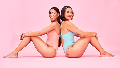 Image showing Diversity, swimwear and women in studio portrait, sitting together with smile and fun body positivity. Beauty, summer fashion and happy bikini models with self love, equality and pink background.