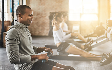 Image showing Exercise, happy man and rowing machine in gym for group class, fitness workout and cardio training. African bodybuilder, athlete and challenge to row on sports equipment for energy, muscle and power