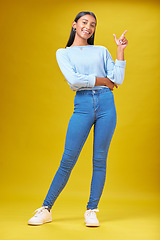 Image showing Pointing, advertising and portrait of a woman in a studio for creative, marketing or promotion. Smile, happy and full length of Indian female model with a direction hand gesture by yellow background.