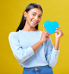 Image showing Portrait, donation and woman with blue heart in studio for help, hope or empathy on yellow background. Face, charity and social media, poster or thank you, support or autism or people with disability