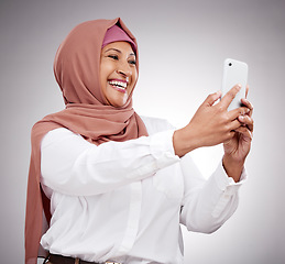 Image showing Woman, muslim selfie and happy in studio for social media, influencer blog with fashion and hijab. Islamic person from Saudi Arabia in profile picture photography and clothes on a white background