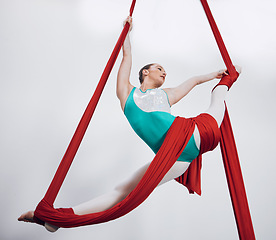 Image showing Flexibility, aerial silk and acrobat woman in air for performance, sports and balance. Gymnastics, athlete person or gymnast hanging on red fabric and white background with space, art and creativity