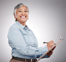 Image showing Clipboard, writing and portrait of senior woman in a studio planning, brainstorming or working on a schedule. Happy, smile and elderly female model with paper list and pen isolated by gray background