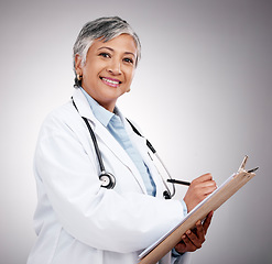 Image showing Happy woman, portrait and doctor with clipboard in studio, planning notes or healthcare information. Mature medical worker writing report of insurance checklist, medicine or script on gray background