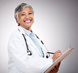 Image showing Woman, portrait and doctor writing on clipboard in studio for notes, healthcare administration or info. Happy mature surgeon with report of insurance checklist, documents or script on gray background