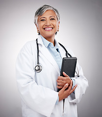 Image showing Tablet, happy woman and portrait of doctor in studio for healthcare services, telehealth support and help. Mature medical worker, digital technology and planning hospital research on gray background
