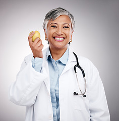 Image showing Doctor, woman and portrait with apple in studio for vitamin c benefits, detox and dietician on gray background. Happy mature nutritionist with fresh fruits for nutrition, healthy food and wellness