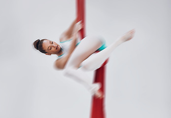 Image showing Gymnastics, woman and aerial silk with a acrobat in air for performance, sports and balance. Young athlete person or gymnast hanging on red fabric and white background with space, art and creativity