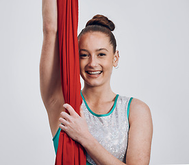 Image showing Portrait, ribbon dancer and competition with a woman in studio on a gray background for routine training. Fitness, smile and energy with a happy athlete holding fabric for a performance showcase