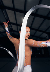 Image showing Woman, portrait and ribbon gymnastics in dance competition, performance and concert in dark arena. Elegant dancer, rhythm and athlete training with talent for creative movement, contest and skill