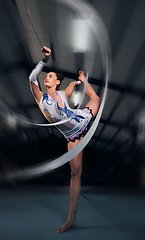 Image showing Woman, dancer and motion for ribbon gymnastics in competition, sports performance or concert in dark arena. Flexible athlete, balance and stretching for creative training, talent or rhythm in contest