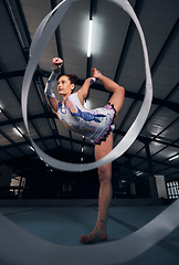 Image showing Woman, dancer and balance for ribbon gymnastics in competition, sports performance or concert in dark arena. Flexible athlete, energy and stretching for agile training, challenge or rhythm in contest