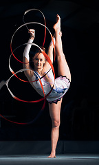 Image showing Woman, portrait and balance for ribbon gymnastics, sports performance or competition in dark concert arena. Flexible athlete, dancer and stretching for agile showcase, challenge and rhythm in contest