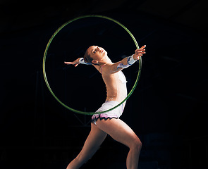 Image showing Dance, training with a gymnastics hoop and a woman in the gym for a performance showcase or practice. Fitness, energy and concert with a female athlete on a dark background for routine or recital