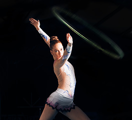 Image showing Fitness, energy with a gymnastics hoop and a woman in the gym for a performance showcase or practice. Dance, training and concert with a female athlete on a dark background for routine or recital