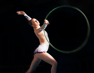 Image showing Portrait, training with a gymnastics hoop and a woman in the gym for a performance showcase or practice. Fitness, dance and concert with a female athlete on a dark background for routine or recital