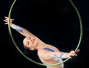 Image showing Portrait, concert with a gymnastics hoop and a woman in the gym for a performance showcase or practice. Training, fitness and energy with a female athlete on a dark background for routine or recital