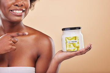 Image showing Hand, pointing and product for beauty, treatment or antiaging with a woman in studio on beige background. Skincare, container and advertising or marketing a lotion for aesthetic wellness or body care