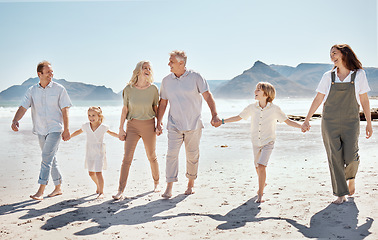 Image showing Happy, walking and big family holding hands at the beach on vacation, holiday or adventure together. Bonding, fun and children with parents and grandparents by the ocean for fresh air on weekend trip