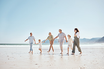 Image showing Travel, walking and big family holding hands at the beach on vacation, holiday or adventure together. Bonding, fun and children with parents and grandparents by ocean for fresh air on a weekend trip.