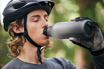 Image showing Forest, biker and man with a water bottle, wellness and exercise with workout, refreshing and break. Healthy person, athlete or guy in the woods, hydration and outdoor with liquid, fitness and helmet