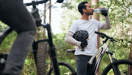 Image showing Forest, bike and man drinking water, exercise and fitness with workout, refreshing and wellness. Healthy person, athlete or cyclists in the woods, hydration and outdoor with liquid, nature and helmet