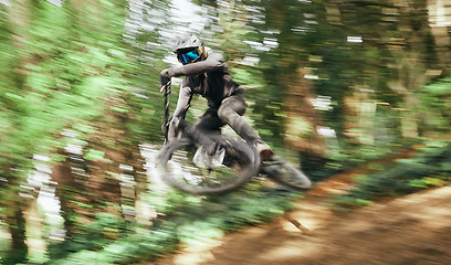Image showing Mountain bike, man and motion jump in forest for competition, challenge and off road adventure. Cycling athlete, sports and fast bicycle in air for action, performance race or power of speed in woods
