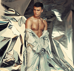 Image showing Fashion, sci fi and silver with a trendy man at a photo shoot in a shiny outfit for futuristic style. Cyberpunk, creative or artistic with a young model in studio for holographic or vaporwave clothes