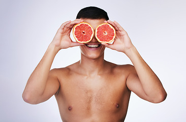 Image showing Beauty, grapefruit and skincare with face of man in studio for health, detox and natural cosmetics. Vitamin c, nutrition and summer with person and fruit on white background for self care and glow