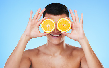 Image showing Happy, lemon and skincare with face of man in studio for health, detox and natural cosmetics. Vitamin c, nutrition and summer with person and fruit on blue background for self care, beauty and glow