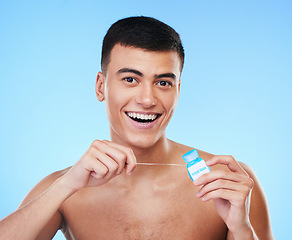 Image showing Happy man, portrait and dental floss for teeth cleaning, hygiene or grooming against a blue studio background. Male person or model smile with flossing in oral, tooth whitening or gum and mouth care