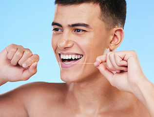 Image showing Happy man, face and dental floss in teeth cleaning, hygiene or grooming against a blue studio background. Male person or model smile with flossing in oral, tooth whitening or gum and mouth care