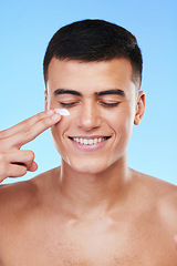 Image showing Skincare, beauty and man in a studio with face cream for a health, wellness and self care routine. Cosmetic, dermatology and young male model with facial spf, lotion or sunscreen by a blue background