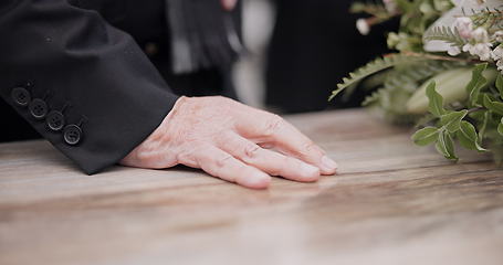 Image showing Death, funeral and hand on coffin in mourning, family at service in graveyard or church for respect. Flowers, loss and people at wood casket in cemetery with memory, grief and sadness at grave burial