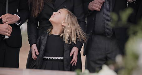 Image showing Mourning, grief and family with girl at funeral, flowers on coffin, death and sad child at service in graveyard. Support, loss and people at casket in cemetery with kid crying at grave for burial.