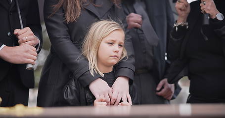 Image showing Child, sad and family at funeral at graveyard ceremony outdoor at burial place. Death, grief and group of people with casket or coffin at cemetery for service while mourning a loss at event or grave