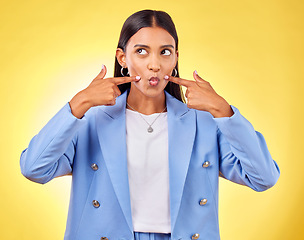 Image showing Face, fingers on cheek and a woman in studio for positive attitude, dimples and emoji. Indian model person or student thinking of fashion, comic and funny face or silly mood on a yellow background
