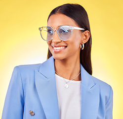 Image showing Young business woman, sunglasses and studio with thinking, vision and smile by yellow background. Entrepreneur, fashion model and happy with stylish frame, lens and trendy suit with ideas for beauty