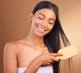 Image showing Smile, hair care and woman with a brush, glow and natural beauty on a brown studio background. Person, girl or model with style, luxury or shampoo with texture, comb or cosmetics with shine or volume
