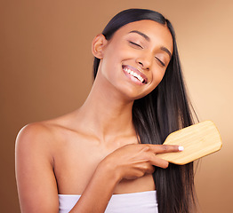 Image showing Happy, hair care and woman with a brush, shine and texture on a brown studio background. Person, girl and model with style, luxury or shampoo with natural beauty, comb or cosmetics with shine or glow